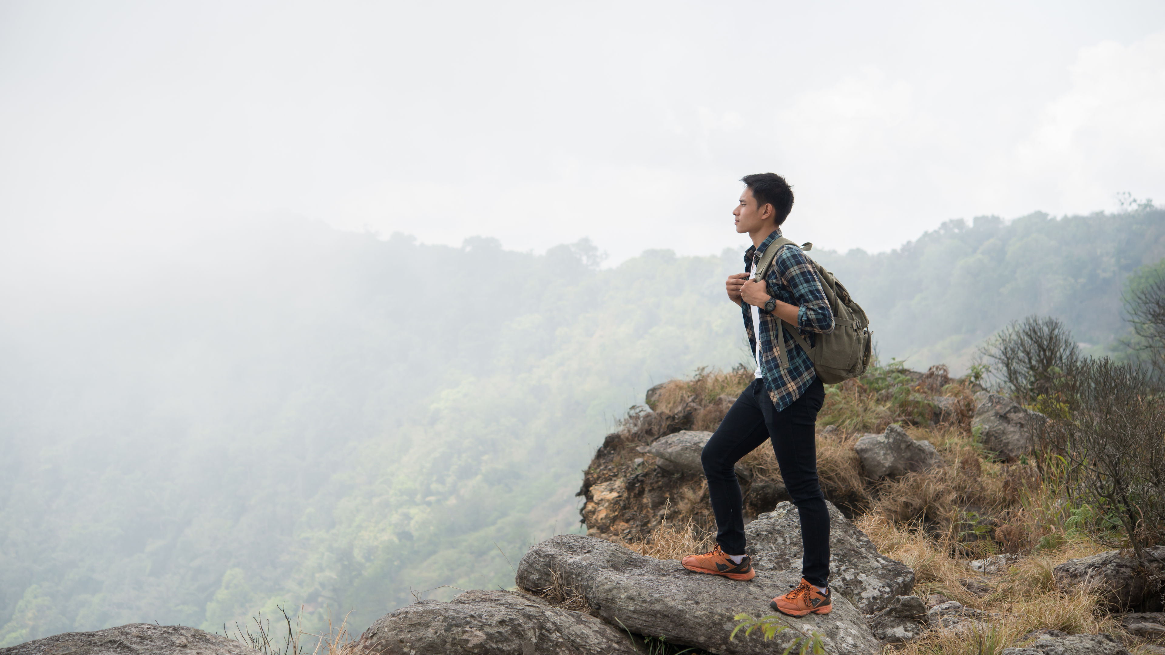 A hiker stands on a rocky hill, carrying a backpack