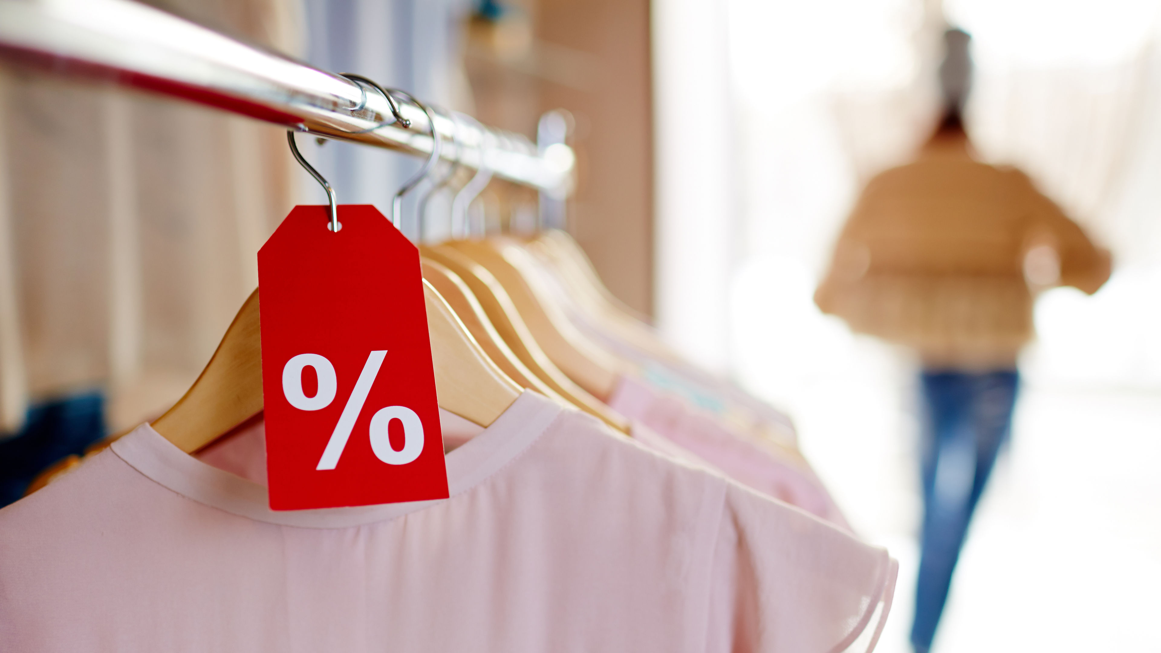 A row of dresses hangs on a rack with a red discount tag in front. 