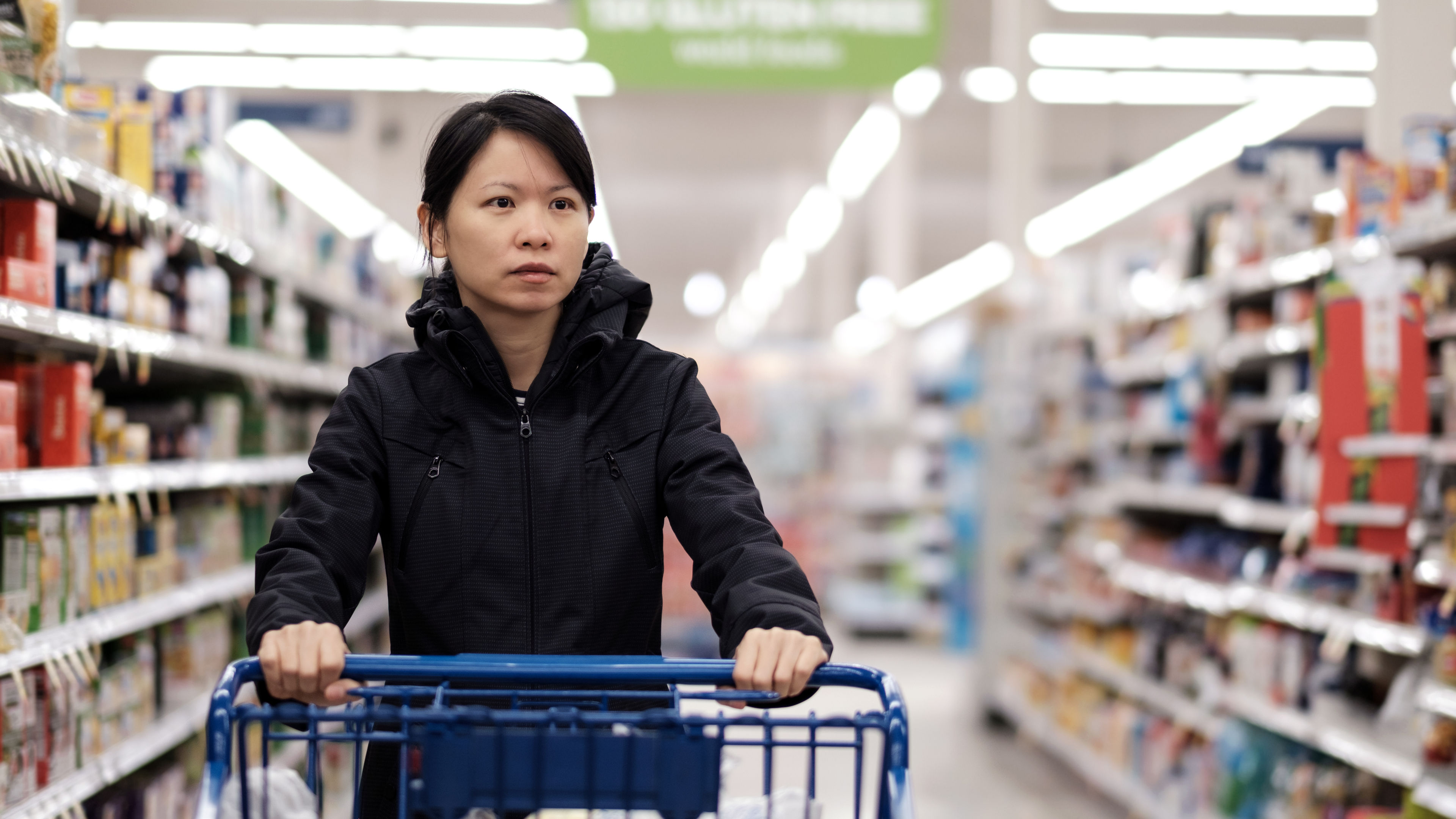 asian woman doing groceries shopping in supermarket with a trolley