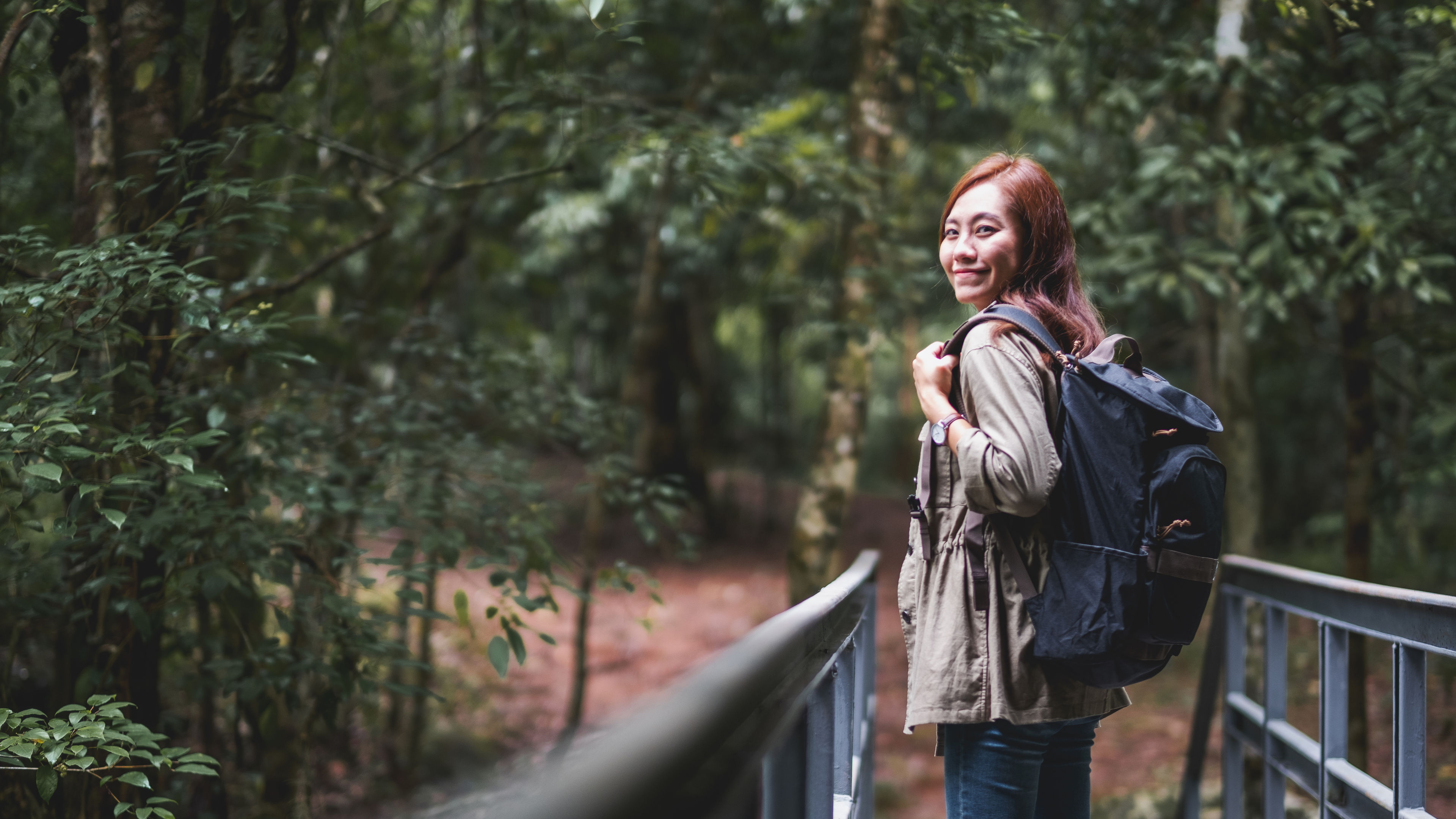 A female traveler with backpack walking into the woods 