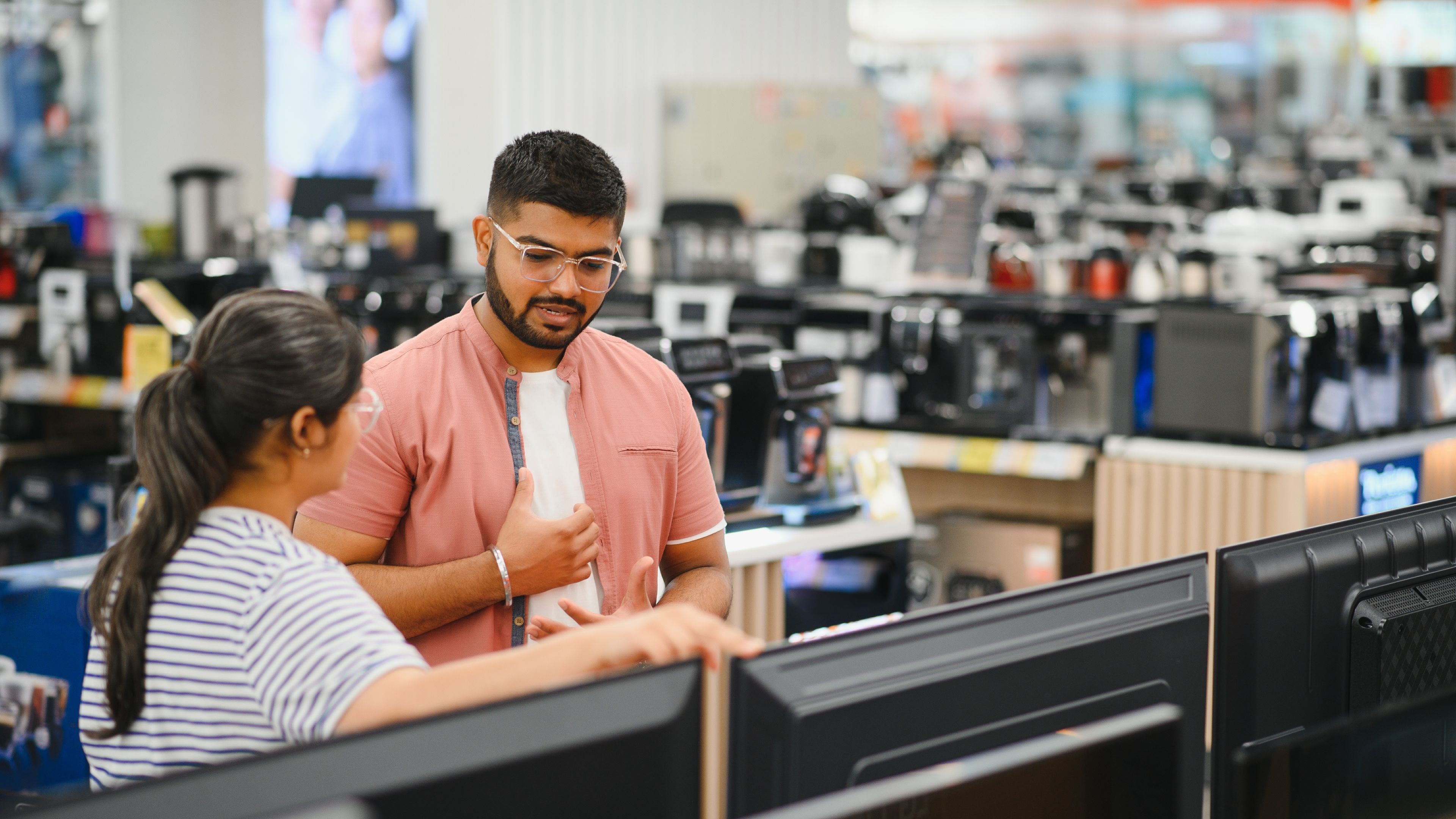 A beautiful couple shops for consumer tech products in a modern home appliances store. 