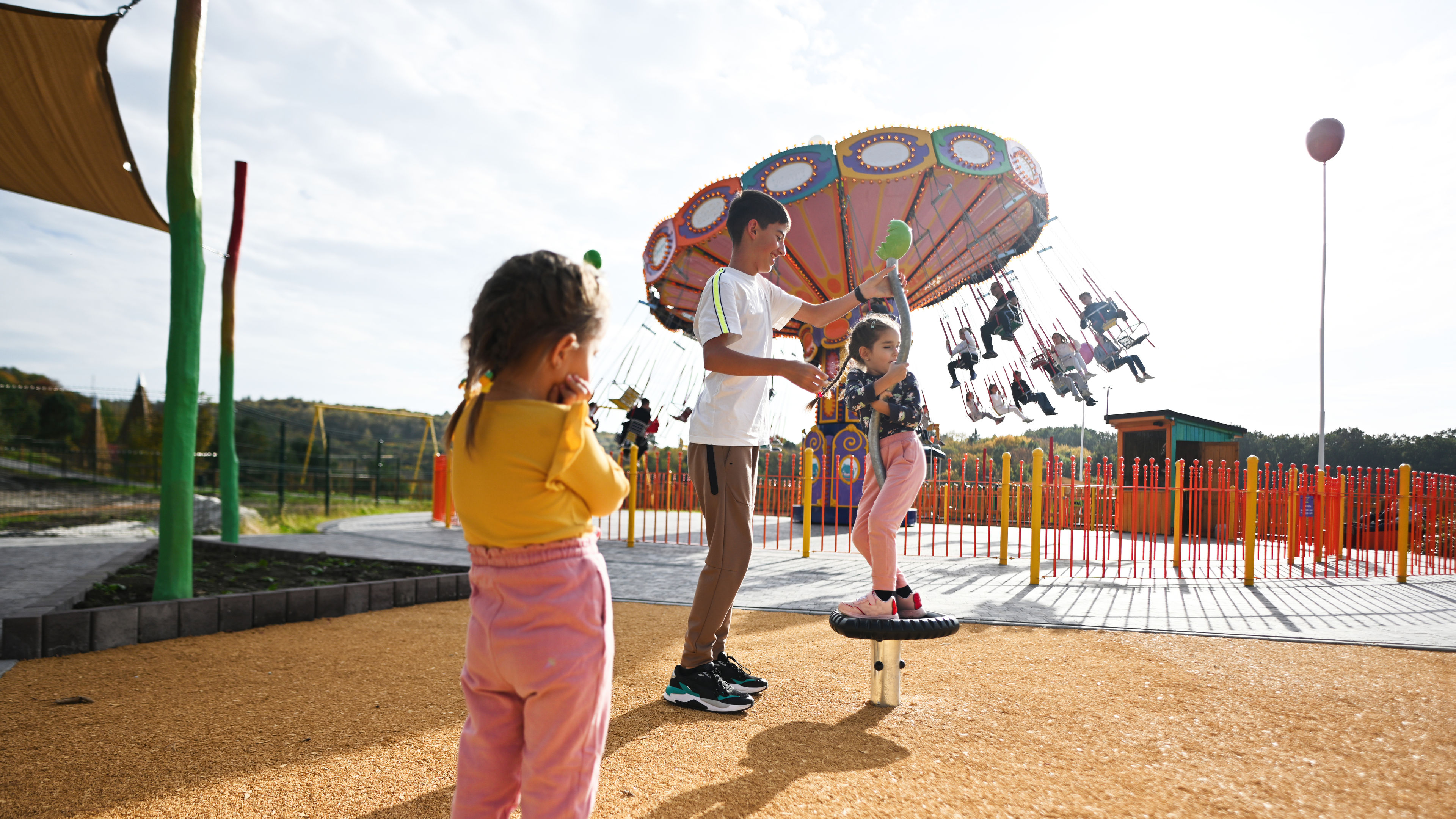 Children are happily playing in the amusement park, laughing as they enjoy various rides.  