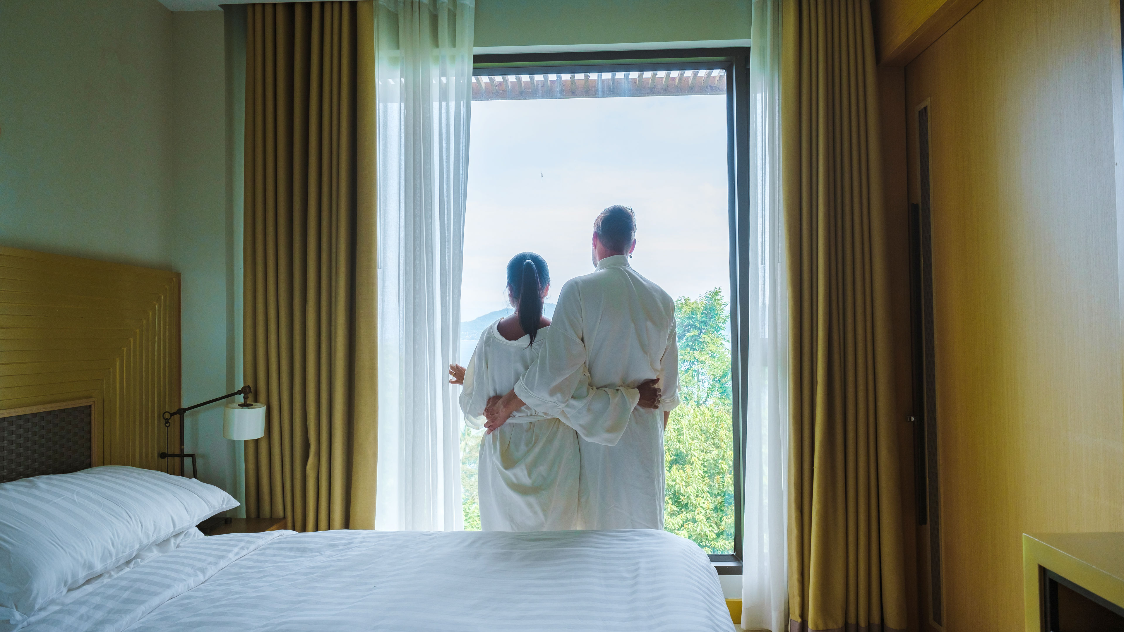 Couple in a hotel room looking out over the window 