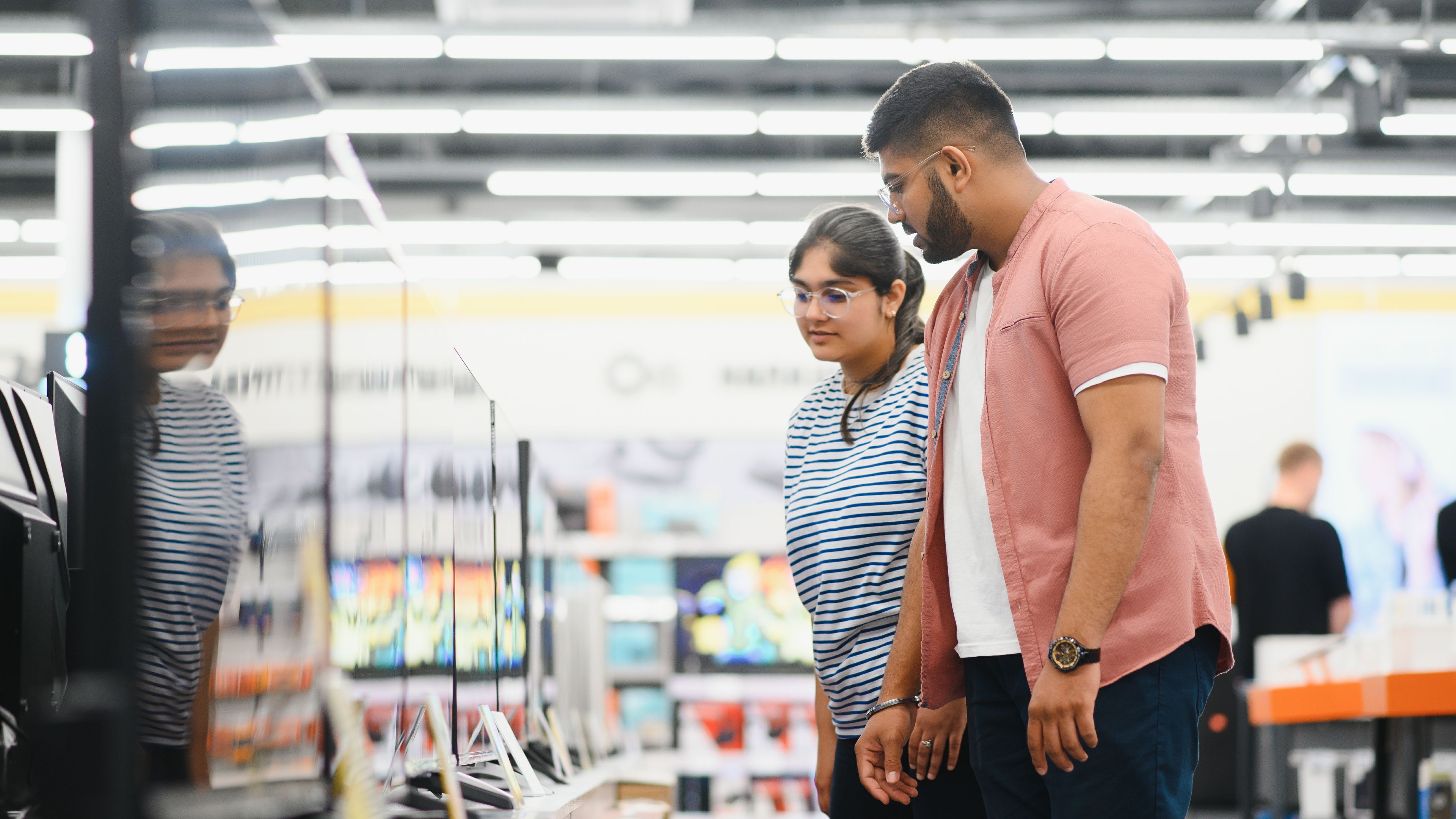The couple is shopping together, browsing for a new TV to enhance their home entertainment experience.