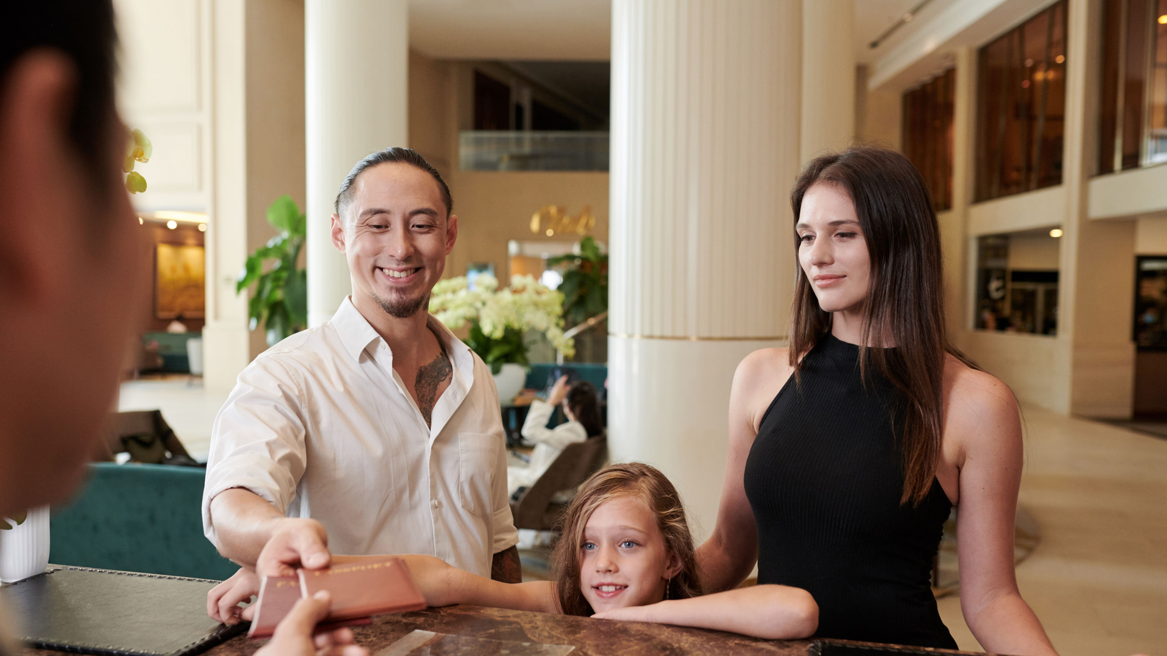 A family checking in at a hotel, completing the check-in process at the reception desk, with staff assisting them and the family members ready to enjoy their stay. 