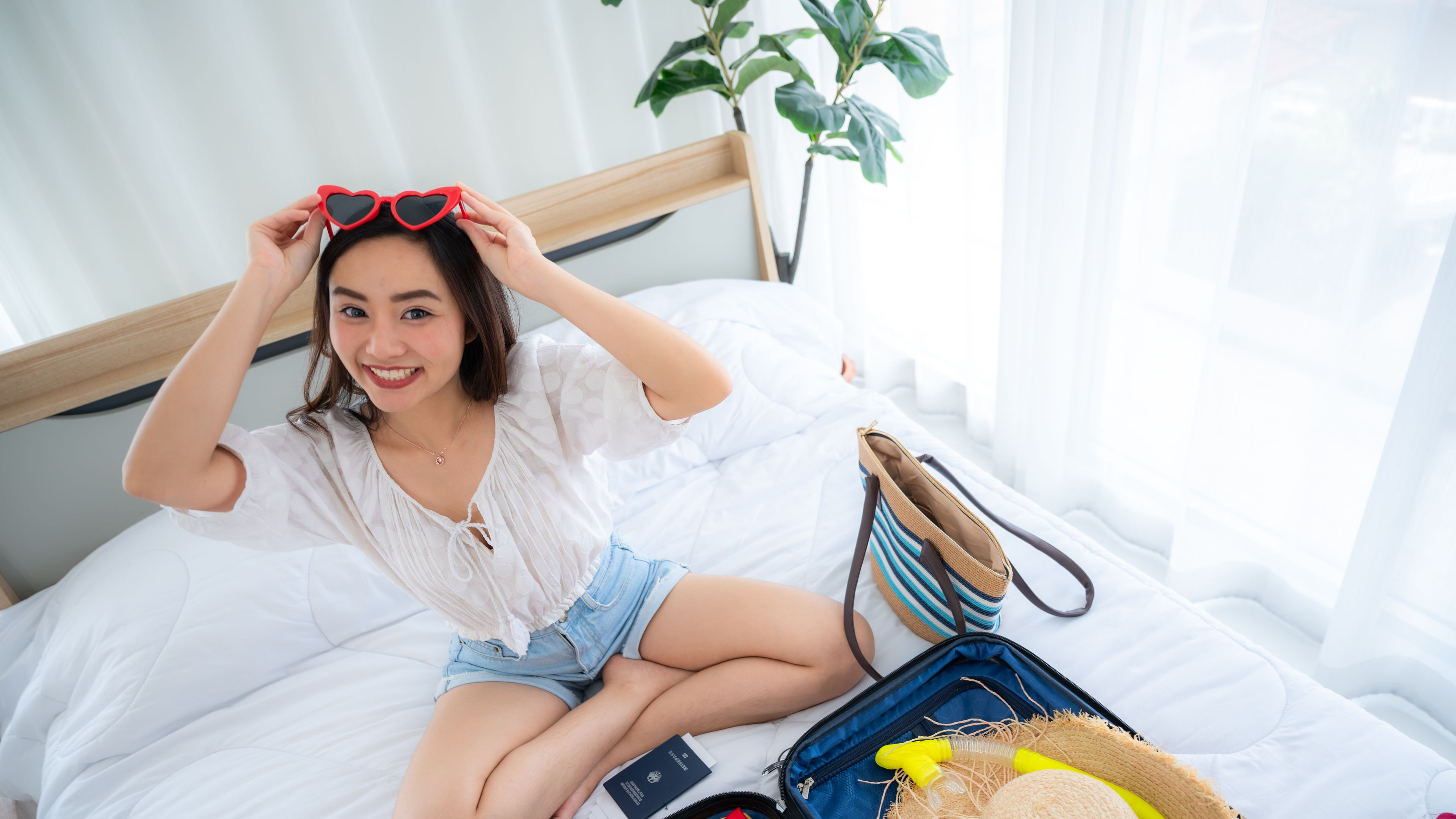 happy beautiful asian woman packing cloth bikini for a long journey 