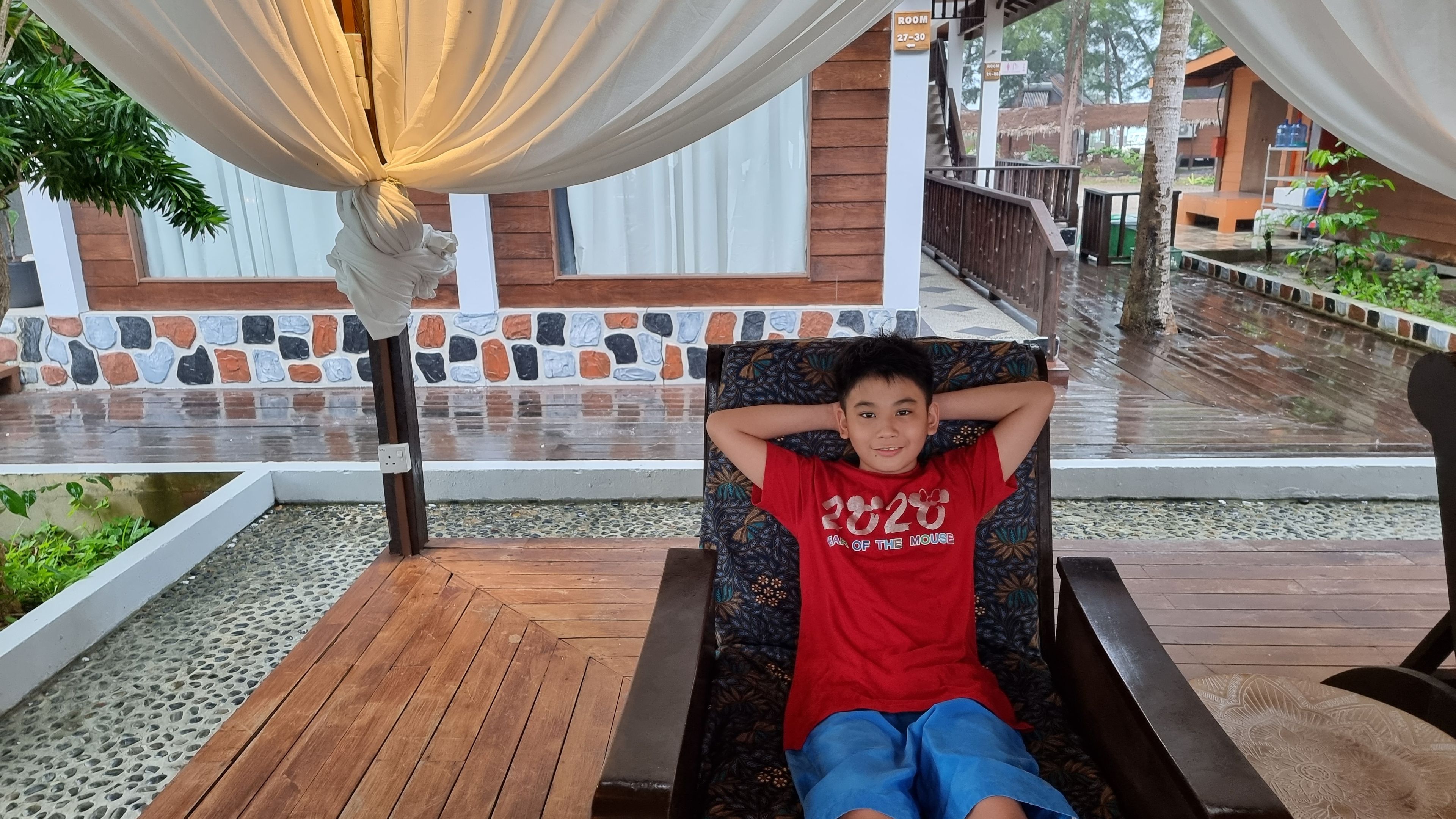 A happy boy is relaxing on a comfy chair under at a peaceful resort,  