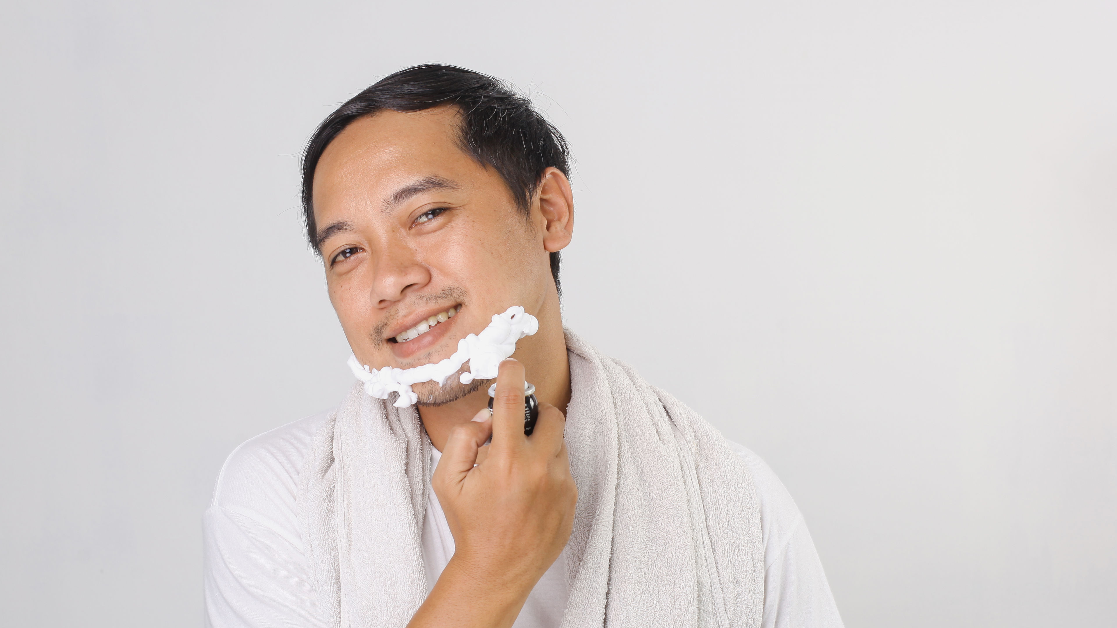 A man carefully shaves his face in front of a mirror 