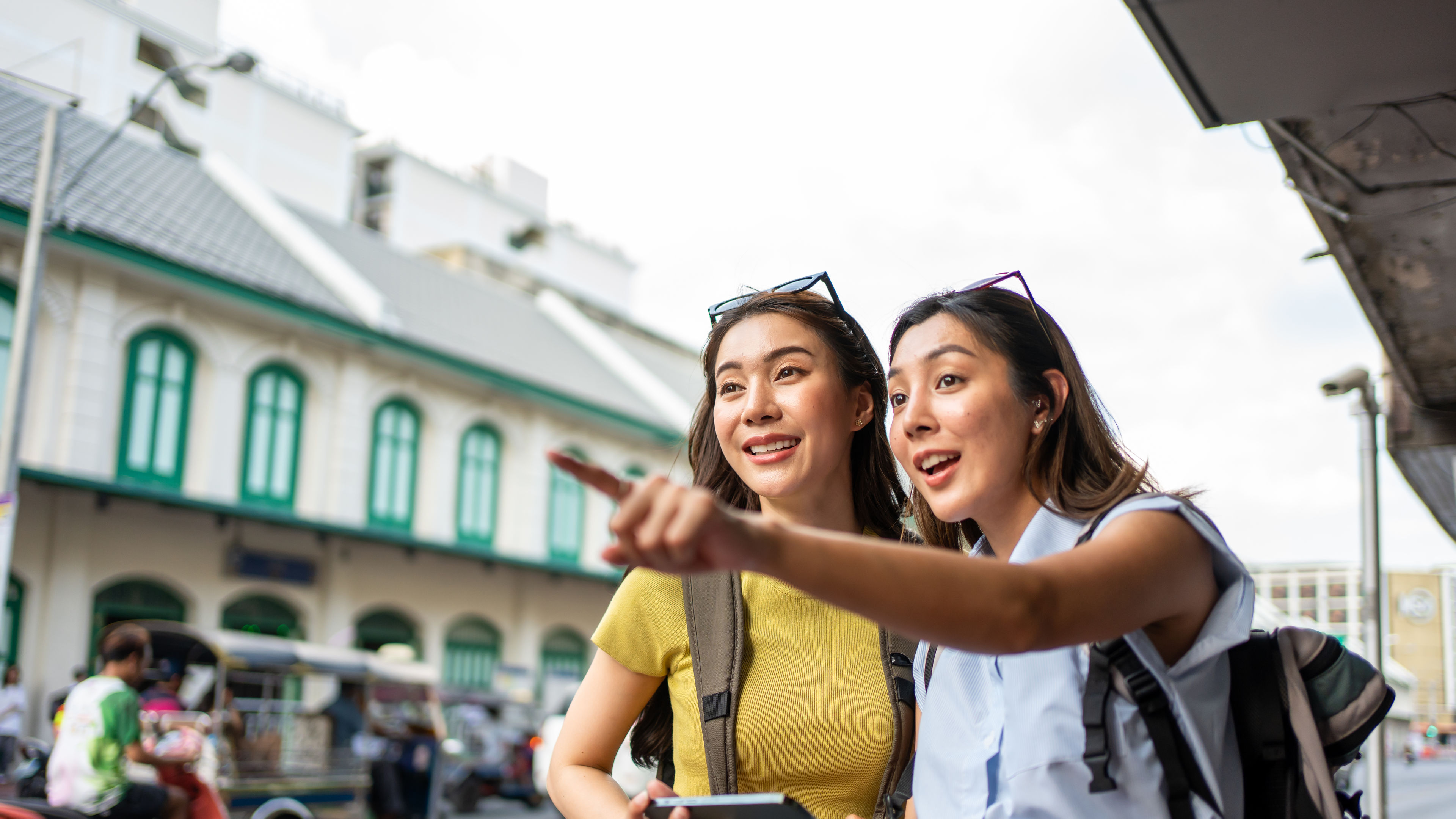 Two cheerful women with backpacks are exploring the city