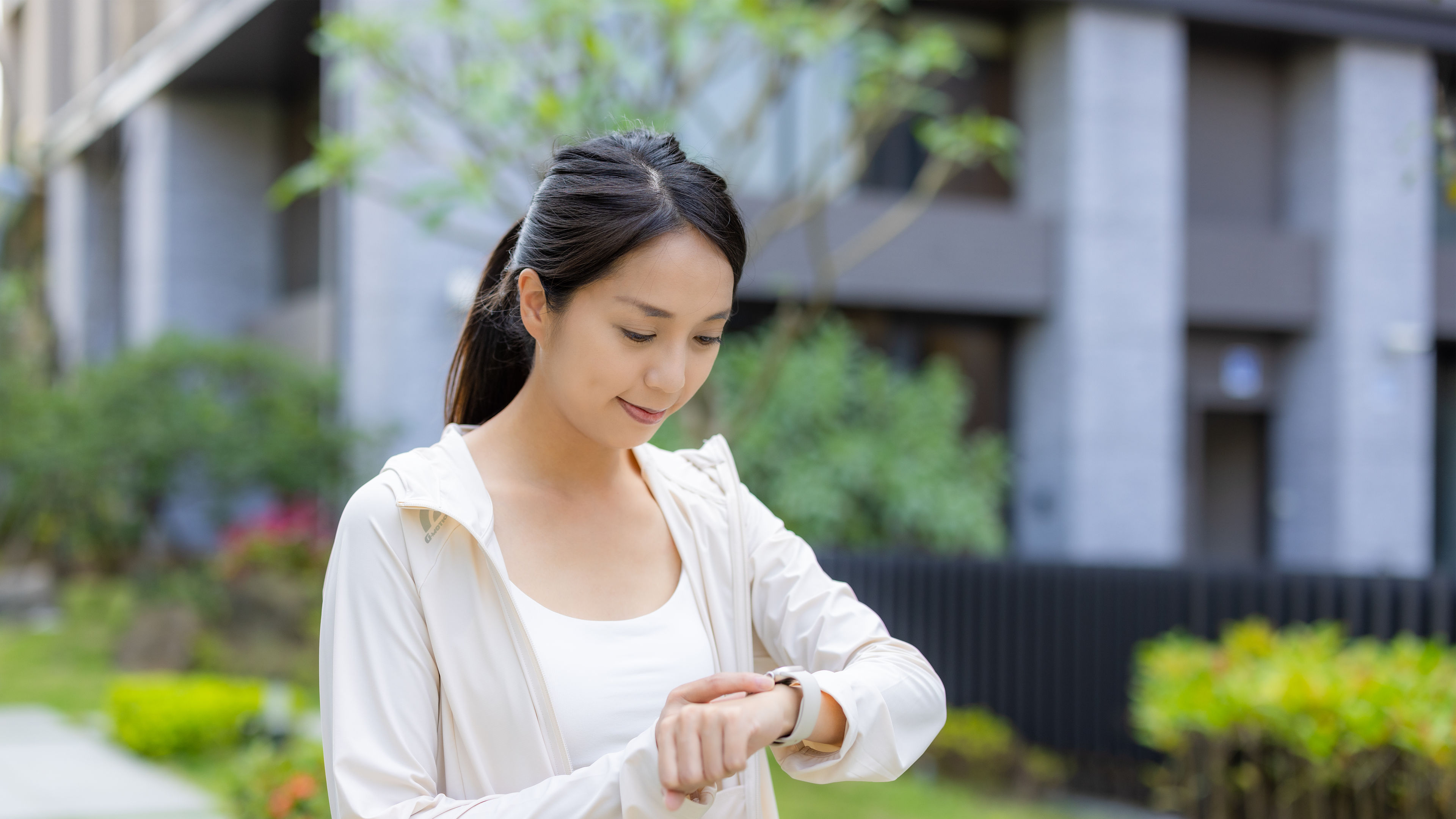 A woman uses her smartwatch outdoors, glancing at its screen.  