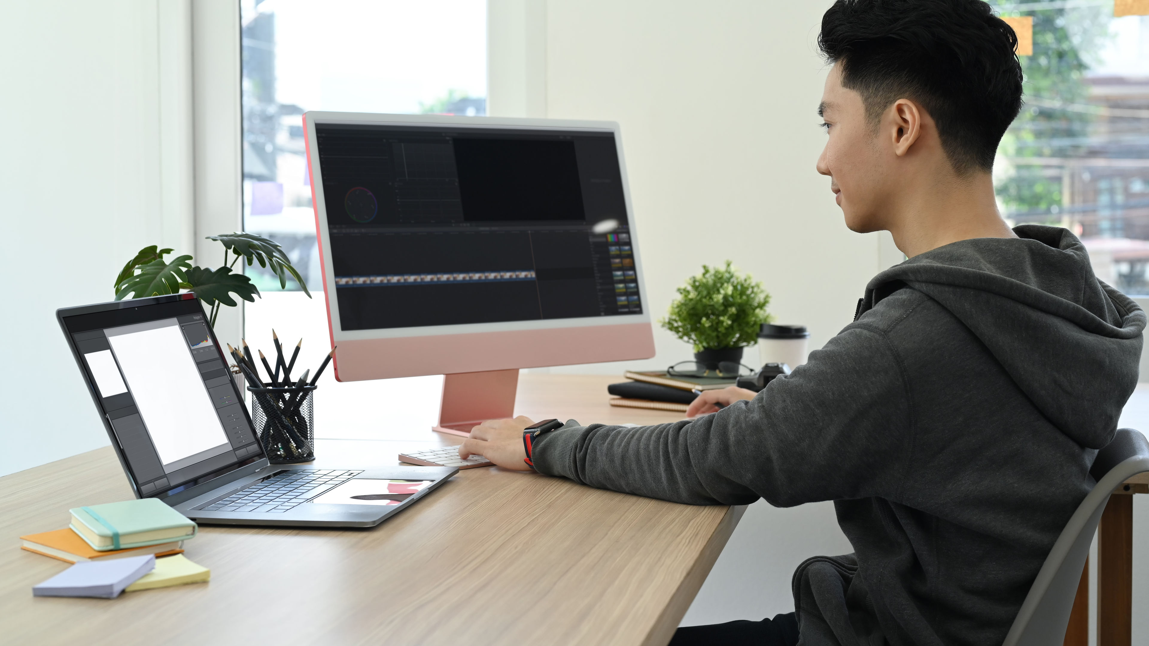 A focused young man works on his laptop at a modern desk 