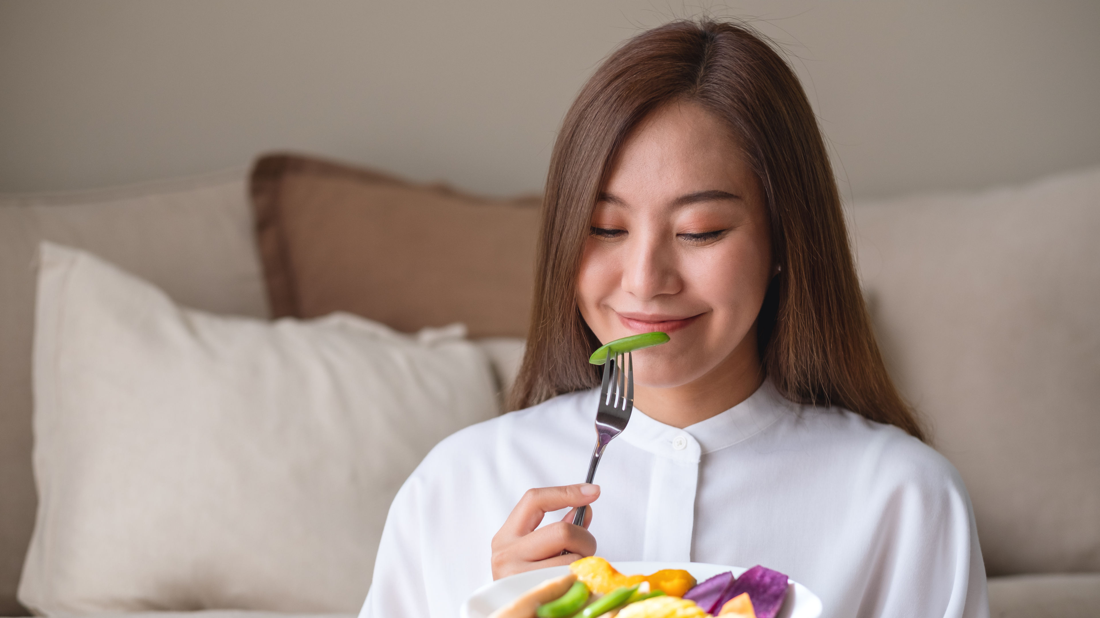 A young woman enjoys a vibrant plate of fresh, colourful vegetables 